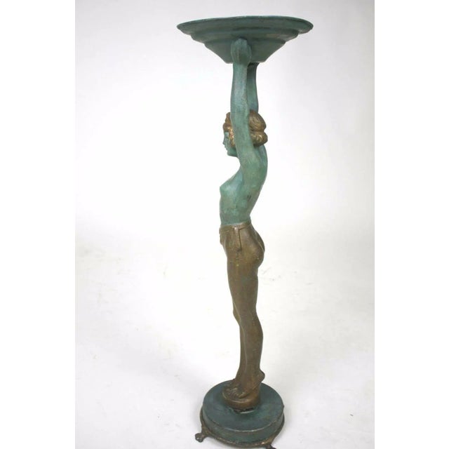 An artful mixed metal Art Deco Lady holding, with arms raised, a round bowl tray aloft a round base with paw feet by...