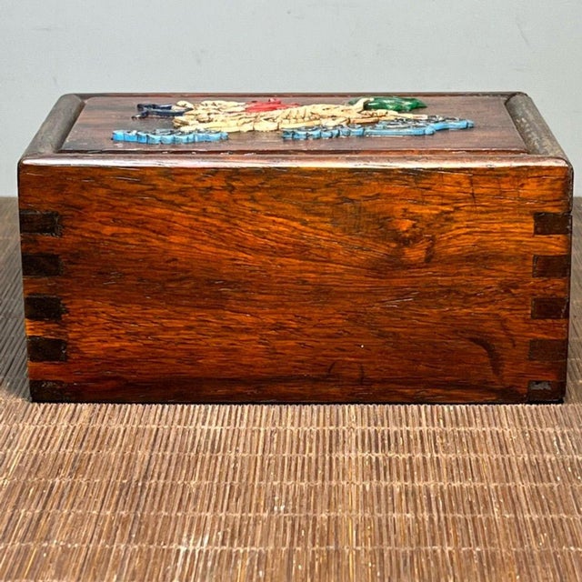 A carved hardwood sliding drawer box with a richly detailed front panel inlaid in bone, depicting an auspicious mythical...