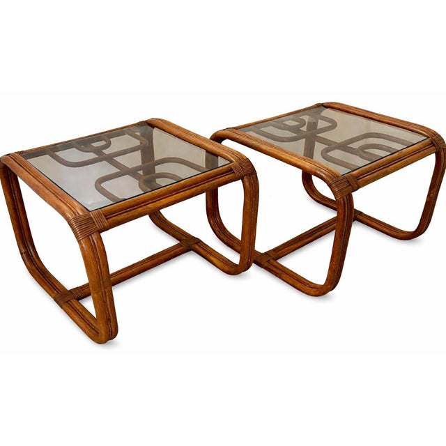 Pair of stylish vintage 1970s rattan side tables with smoked glass top. Elegant geometric design. Crafted from natural...