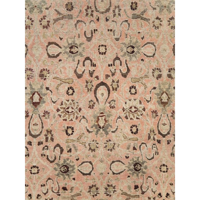 This early 20th-century Persian Tabriz carpet presents a refined allover floral composition across a soft salmon-pink...