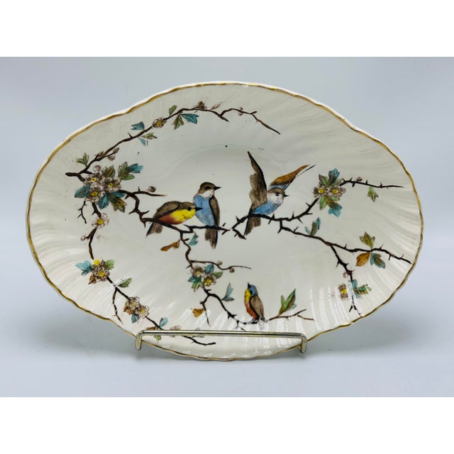 This is a lovely antique porcelain serving bowl or platter featuring a delicate hand-painted bird and blossoming branch...