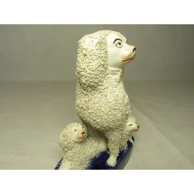 Antique Staffordshire poodle group, c.1880 An unusual form with an adult with two pups seated on a deep blue base. With...