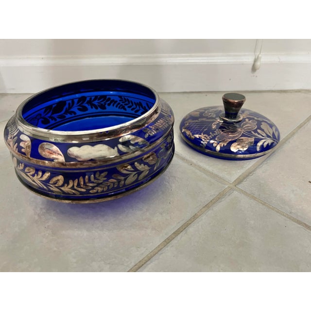 Early 20th century wide cobalt blue glass lidded bowl. Beautiful silver overlay floral design. With the lid it stands 7”...