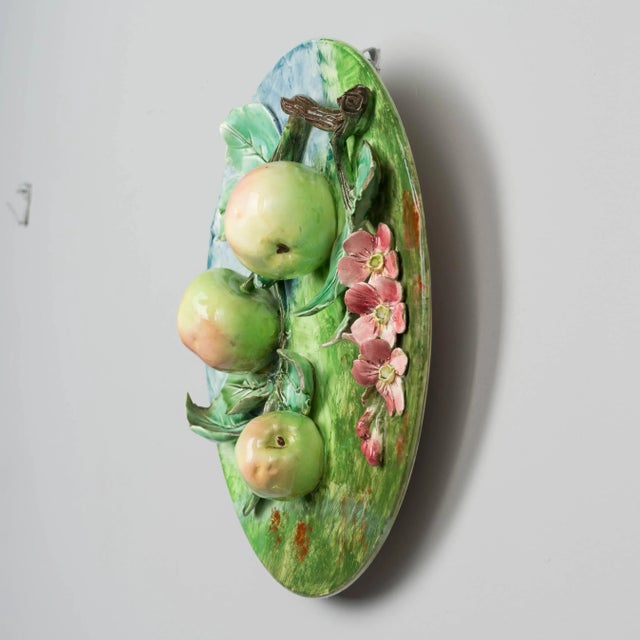 A 19th century French Barbotine Majolica wall platter with three pale pink and green apples hanging from leafy tree branch...