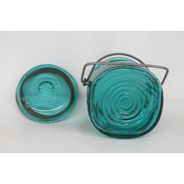 This beautiful vintage Ball Ideal Mason Jar is made out of teal glass with a metal mechanism for securing the matching...