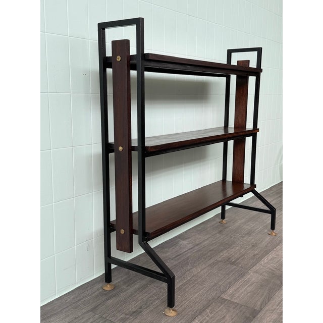 This vintage industrial-style bookcase dates back to the 1970s in Italy. The piece features a geometric black-painted iron...