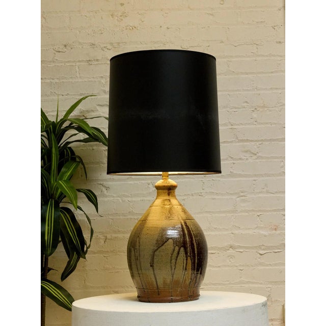 A handsome vintage table lamp featuring a rounded, substantial base with an earthy glazed finish. Layers of warm brown,...