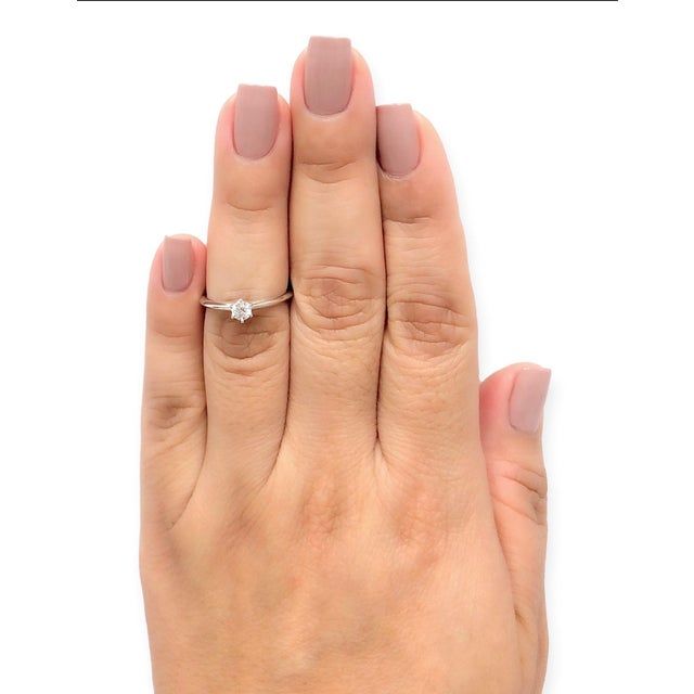 Classic Tiffany & Co. platinum solitaire featuring a 0.28 ct round brilliant cut diamond securely prong-set on a sleek,...