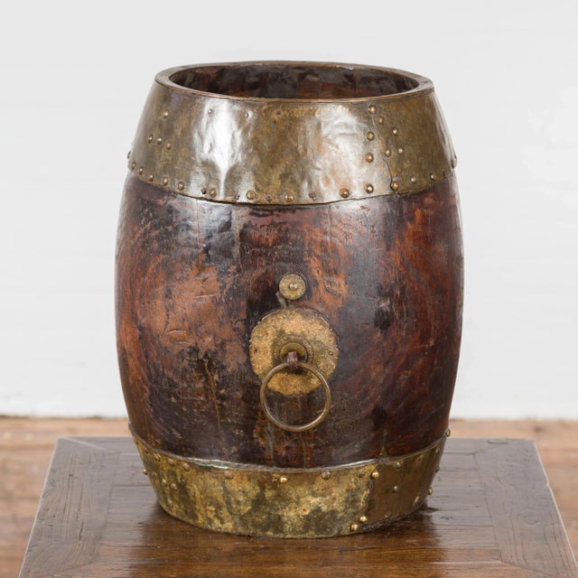 A Chinese vintage wooden bucket from the mid 20th century, with brass accents. Created in China during the midcentury...
