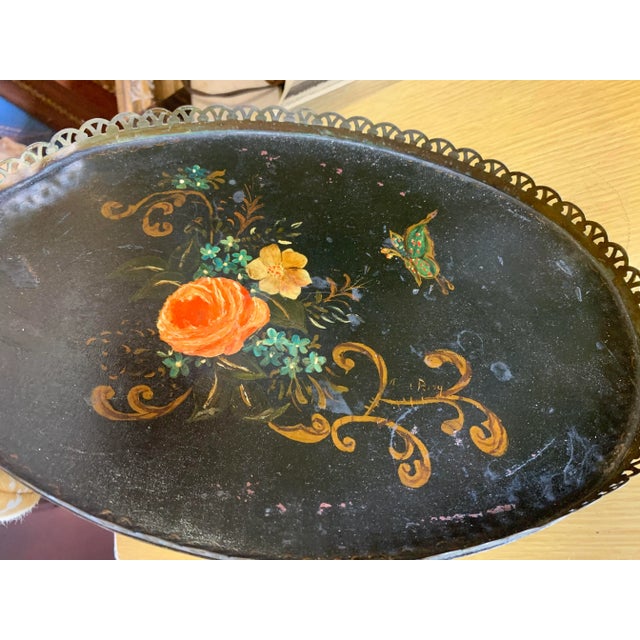 Vintage black tray with painted flowers. Oval in shape with filigree border.