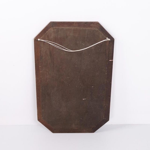 Rectangular mirror with a carved dark wood frame dating from the 1940s. It features classic decorative details and is...