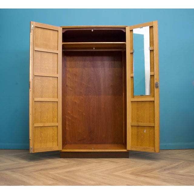 A well-made mid-century double wardrobe in a warm golden oak finish, with a subtle figured grain across the doors. Simple,...