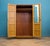 A well-made mid-century double wardrobe in a warm golden oak finish, with a subtle figured grain across the doors. Simple,...