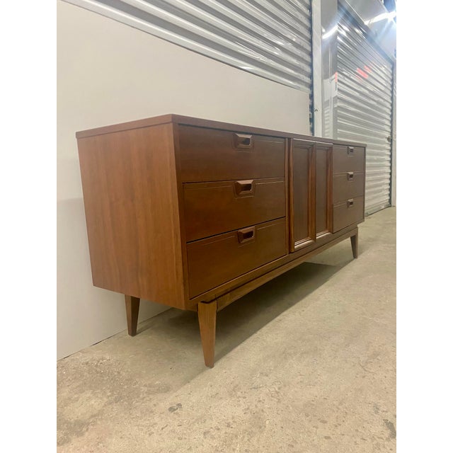 This mid-century modern credenza is a United Furniture piece featuring a walnut finish and characteristic tapered legs....