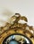This convex mirror in giltwood, crafted in England during the 19th century, reflects the enduring influence of the Regency...