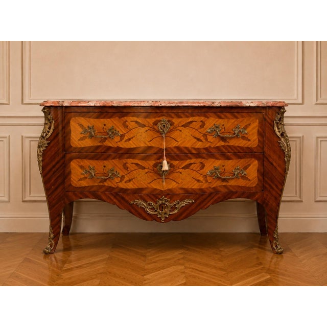 This elegant early 1900s French Louis XVI–style commode combines warm fruitwood, delicate floral marquetry, finely cast...