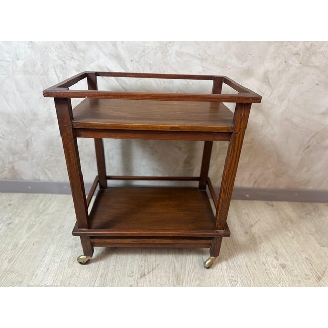 A charming rolling wooden serving cart dating from the 1940s, with clean, geometric lines. Its warm brown hue highlights...