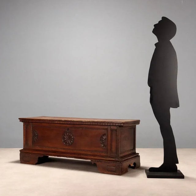 Walnut chest, carved front panel with a central rosette and half-rosettes on the sides. Bracketed legs, missing lock,...