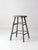 Antique wood stool with a round seat, splayed legs, and double-stretcher construction, finished in a softly weathered gray...