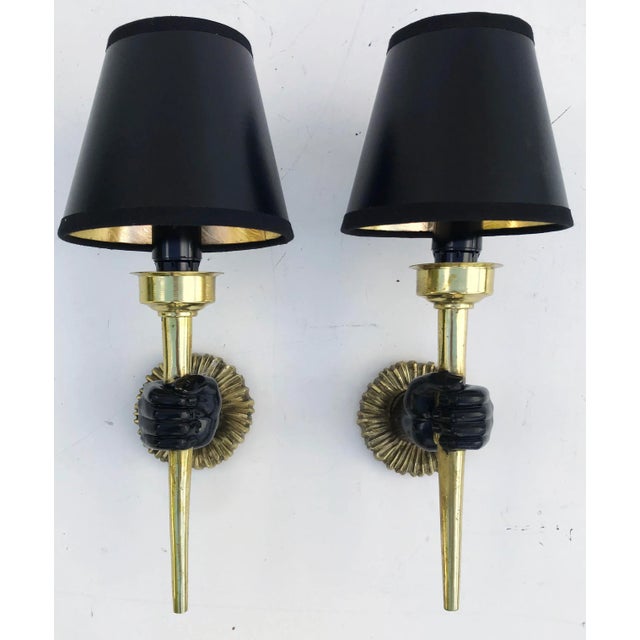 Pair of brass sconces handling a torch by John Devoluy. 60w each. Priced by pair Provenance: Parisian hotel US wired and...