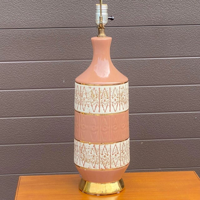 An original vintage mcm style ceramic table lamp with salmon glaze and gold trim. Lamp base 20” tall to top of bulb...