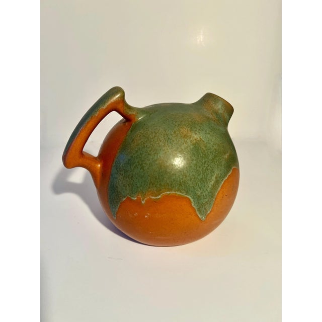 A wonderful hand crafted pottery terra cotta pitcher with earthenware color and a green accent. The pitcher is round with...
