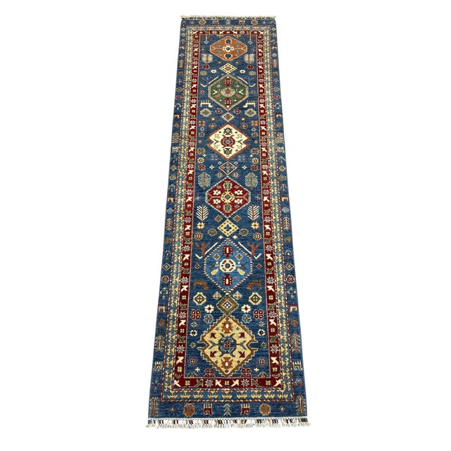 This Kazak style runner rug has a deep blue field with a row of large, colorful medallions. Rust red, ivory, green, and...