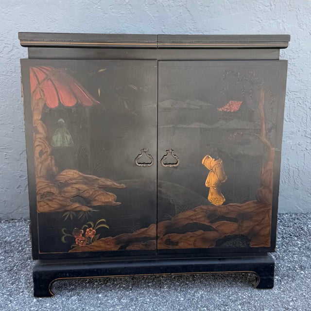 A charming vintage Chinese dry bar featuring a black lacquered finish with hand-painted landscape scenes in warm red,...