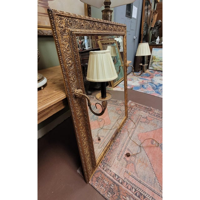Beautiful rare vintage beveled glass gilt wall mirror with candelabras. Features a 4 inch wide intricate gilt frame, two...