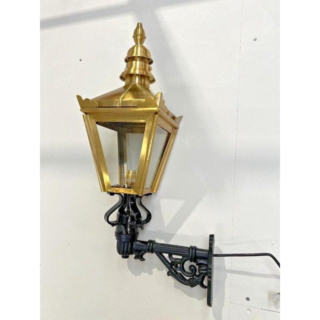 A handsome traditional brass wall lantern with decorative cast iron mounting bracket, combining classic architectural...