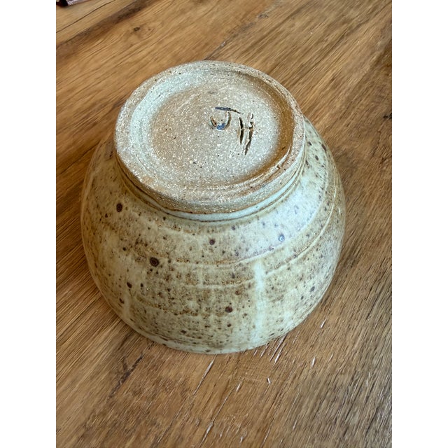 In the style of a Hagi ware pottery bowl, a traditional Japanese ceramic style: The bowl features a creamy, off-white...