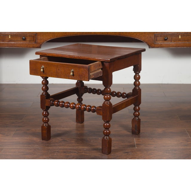 An English oak bobbin legs side table from the late 19th century, with single drawer and stretchers. Created in England...