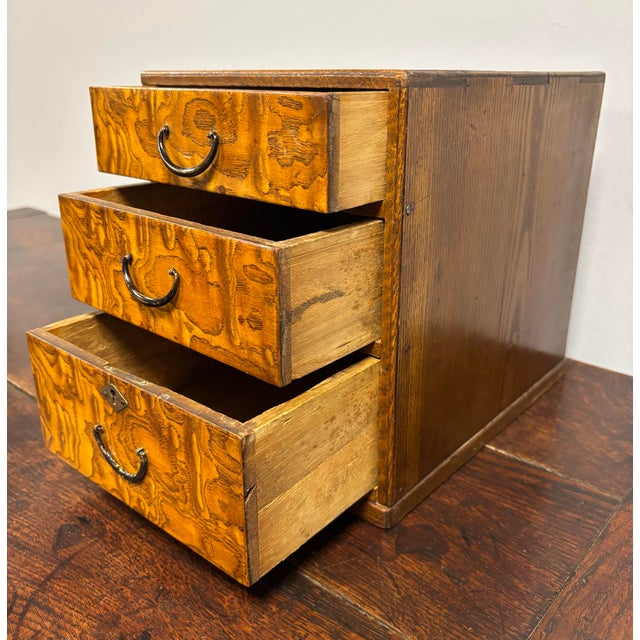 This exquisite antique English tabletop chest of drawers is a rare and charming piece, possibly crafted as a salesman’s...