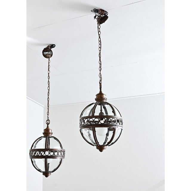 A magnificent pair of early 20th century English pendant light fixtures in globe form–very similar to an armillary...