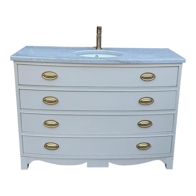 Elegant vintage bow-front dresser thoughtfully converted into a distinctive single-sink bathroom vanity. The cabinet...