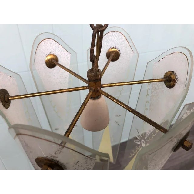 Suspended chandelier of Italian manufacture of the 50s structure in brass and with the lampshades in decorated glass...