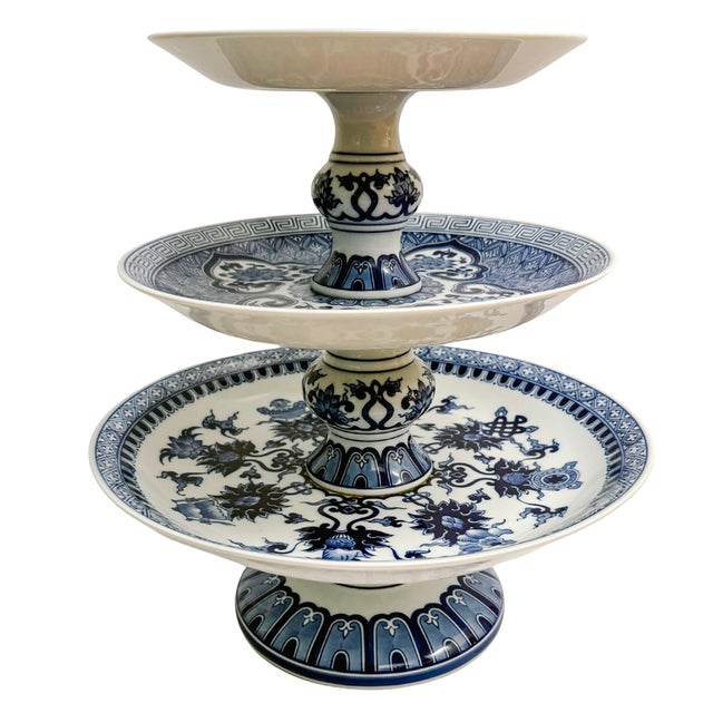 An elegant, large three-tier serving stand features a classic blue and white Chinoiserie aesthetic, perfect for adding a...