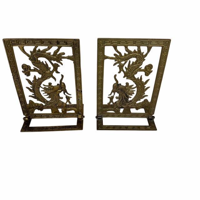 Vintage mid century folding brass bookends featuring a Chinese dragon design and a Greek key border. Standing measures4.5”...