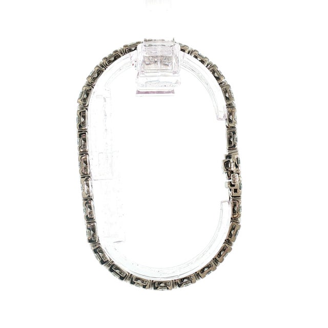 A 14k white gold, unique, triangular-setting tennis bracelet. This piece features 56 brilliant-cut white diamonds with a...