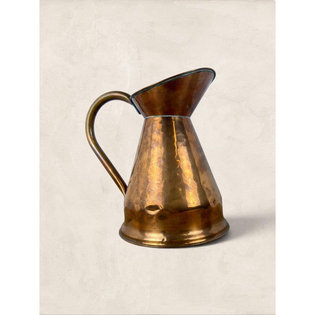 A beautifully proportioned antique English hammered copper water ewer dating to circa 1920. Featuring a flared pouring...