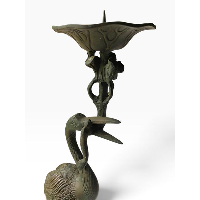 A vintage Japanese bronze pricket candlestick featuring a crane standing on a turtle and holding a lotus leaf candle pan...