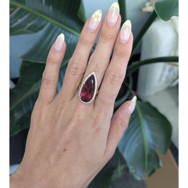 A vivid 12.9CT Rubellite radiates rich crimson fire, encircled by a sparkling halo of earth-mined diamonds. Set in solid...