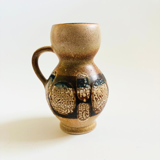 A mid century pottery vase produced by Lapid Pottery of Israel. Finished in a layered fat lava glaze of earth tone colors....