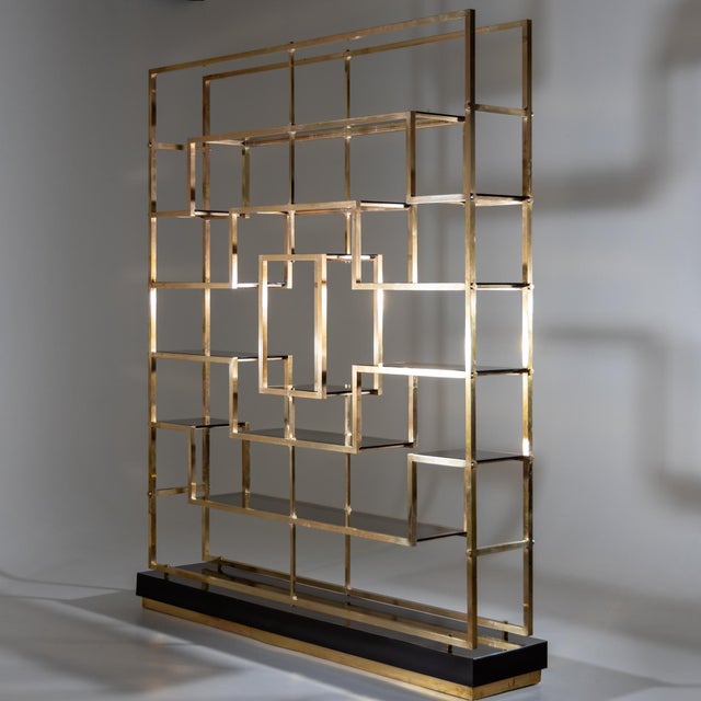 A large brass and smoked glass etagere designed by Kim Moltzer. Crafted in heavy brass with black base.