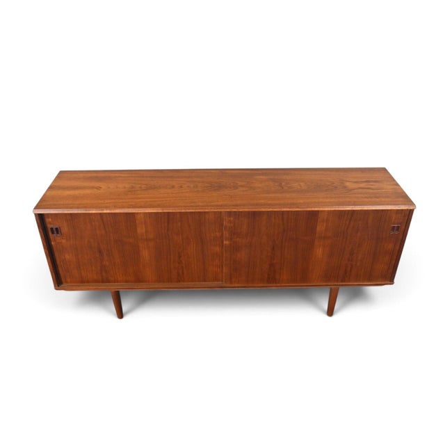This credenza was made in Denmark during the 1960s, with a teak case featuring square pull hardware on the drawers and...