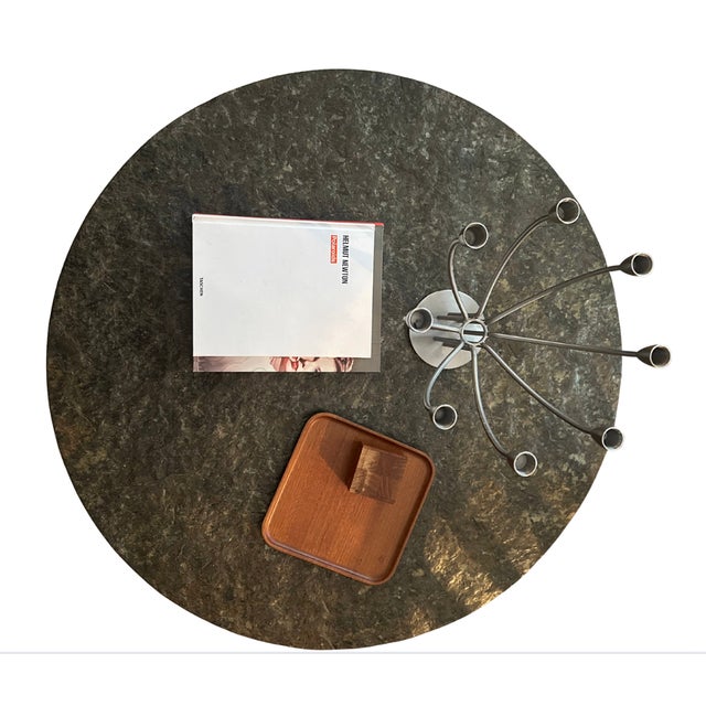 This vintage brutalist coffee table from the 1960s features a distinctive raw slate stone top and rests on three black...