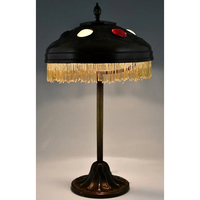 Art nouveau desk lamp in patinated bronze with hammered brass shade and glass inlay. Yellow golden frills. France ca. 1900...