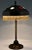 Art nouveau desk lamp in patinated bronze with hammered brass shade and glass inlay. Yellow golden frills. France ca. 1900...