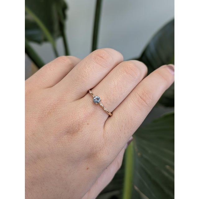 A truly pretty ring with timeless charm — this piece showcases a 4mm Santa Maria Aquamarine, glowing with serene blue...