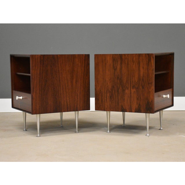 A pair of mid century modern rosewood thin edge nightstands designed by George Nelson for Herman Miller with a single...